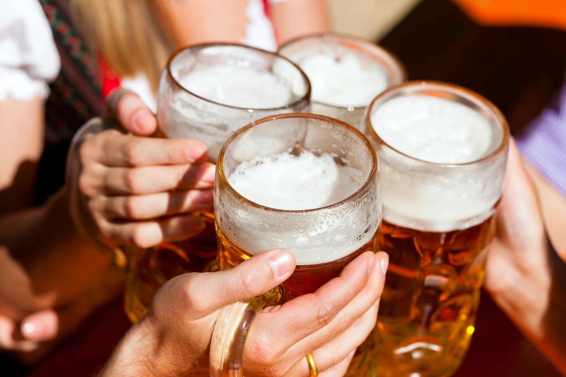 Vier vrienden proosten met bierpullen in een biertuin